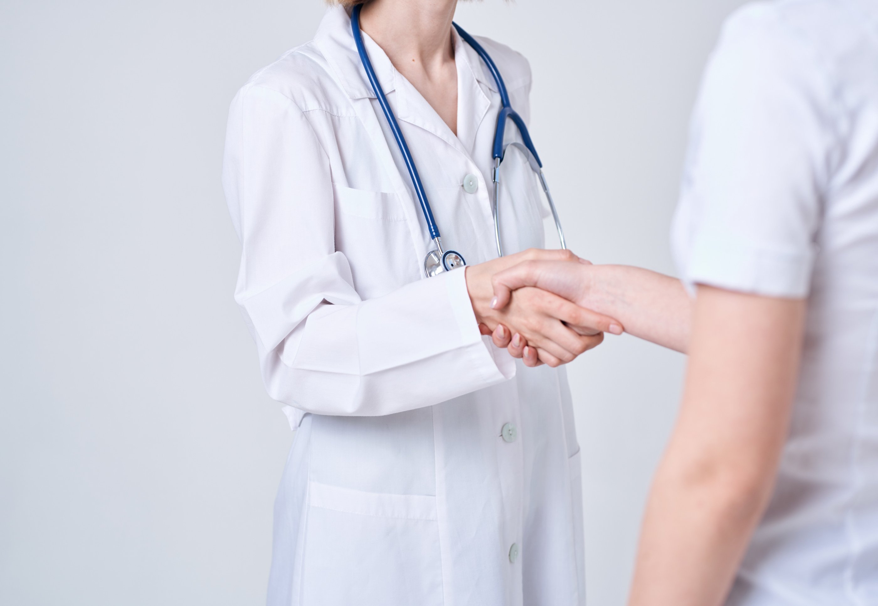 Doctor and Patient Shake Hands with Each Other on a Light Background Cropped View